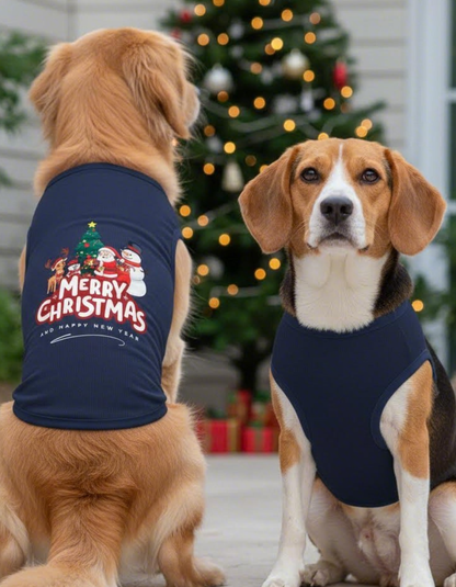 Two dogs wearing navy blue Christmas-themed shirts in front of a decorated Christmas tree.